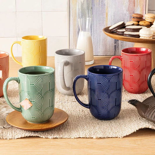 Colorful patterned mugs on a wooden table with a blurred background