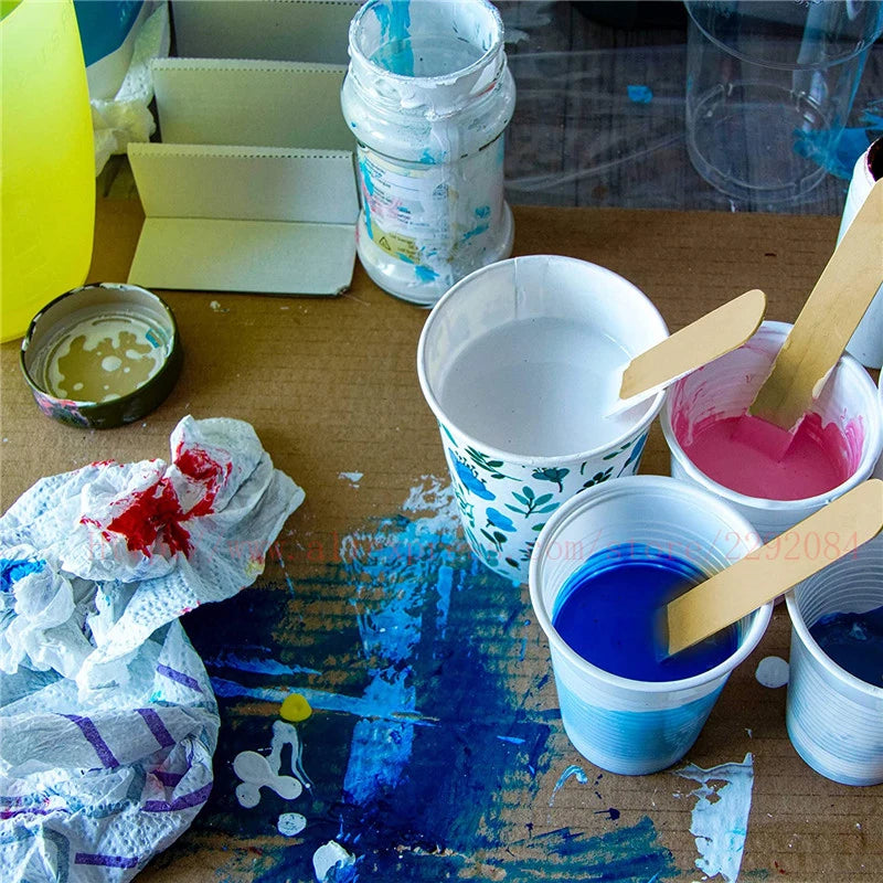 Artistic workspace with paint containers, brushes, and a paint-splattered surface.