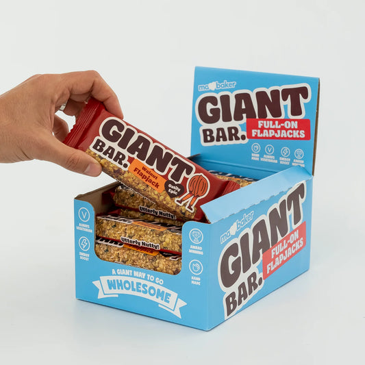 Hand holding a Giant Bar flapjack with open box on a white background