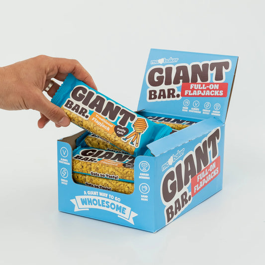 Hand opening a box of Giant Bar Full-On Flapjacks on a white background