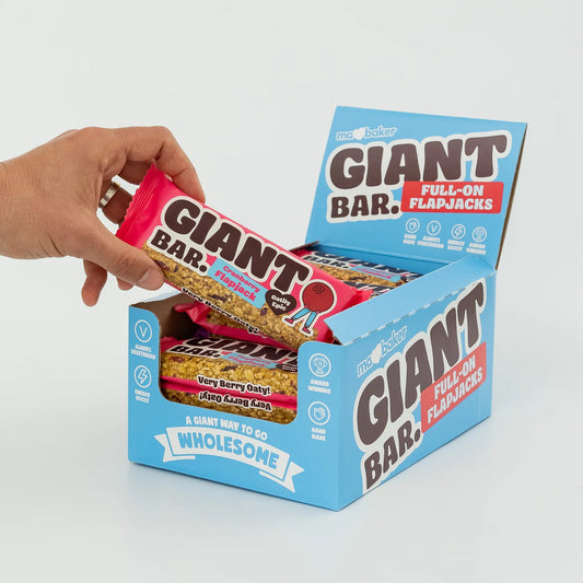 Hand picking a Giant Bar from a box of Flapjacks on a light gray background