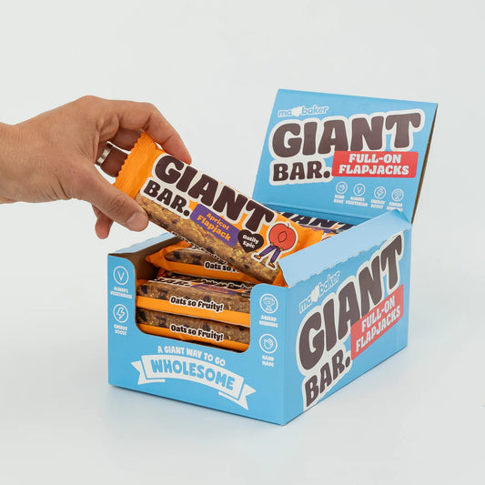 Hand holding a box of Giant Bar Full-On Flapjacks against a light gray background