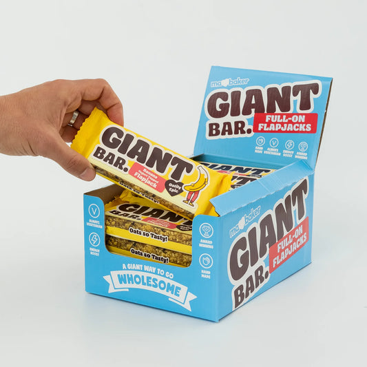 Hand holding a Giant Bar flapjack with open box on a light gray background