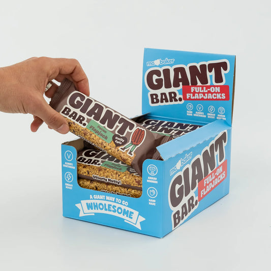 Hand pulling a Giant Bar out of its packaging on a light gray background