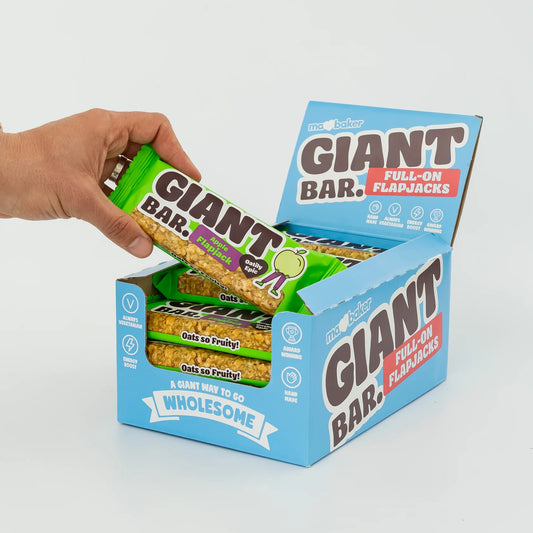 Hand opening a box of Giant Bar Full-On Flapjacks with a white background