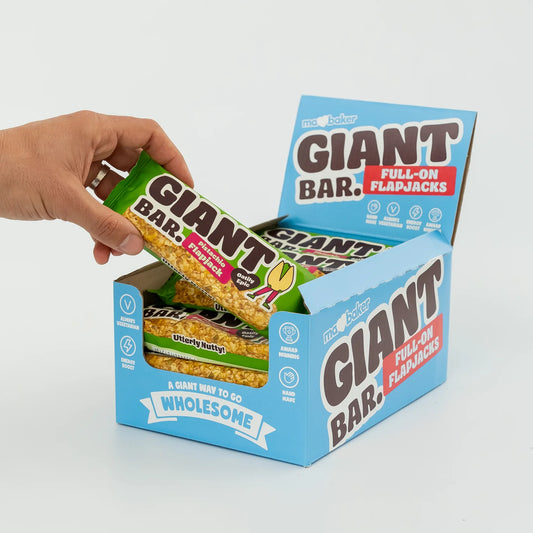 Hand opening a box of Giant Bar Full-On Flapjacks on a light gray background