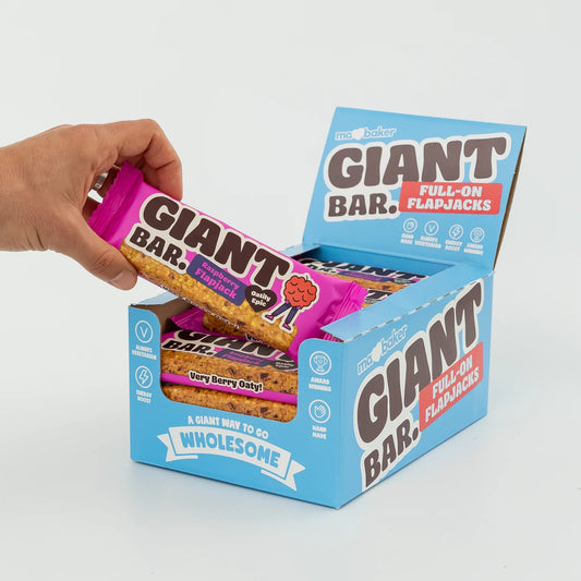 Hand opening a box of Giant Bar Full-On Flapjacks with a focus on the product packaging.
