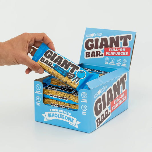Hand reaching for a Giant Bar Full-On Flapjacks bar from its packaging on a light gray background
