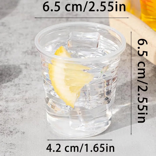 Clear plastic cup with a lemon slice in water, showing dimensions on a gray surface.