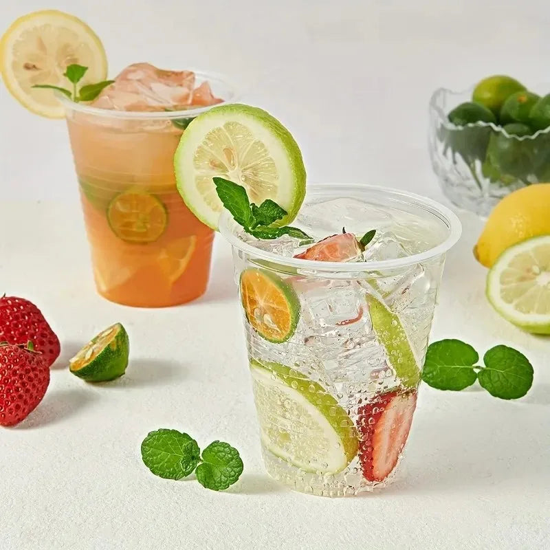 Two glasses of fruit-infused drinks with lemons, limes, and strawberries on a white surface.