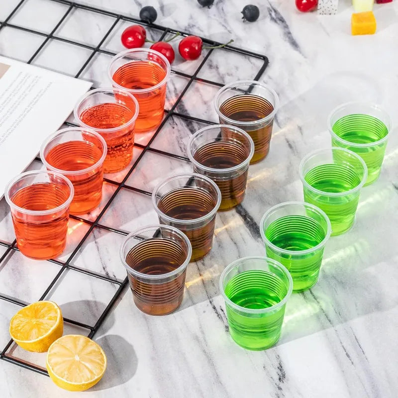 Colorful shot glasses filled with different colored liquids on a marble surface.