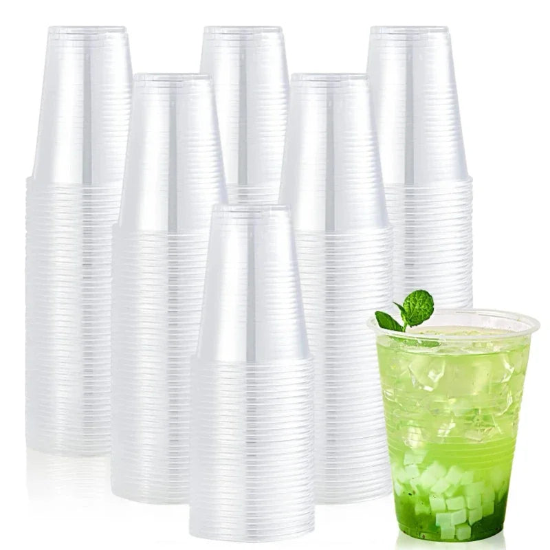 Stack of clear plastic cups with a green drink and mint leaves on a white background